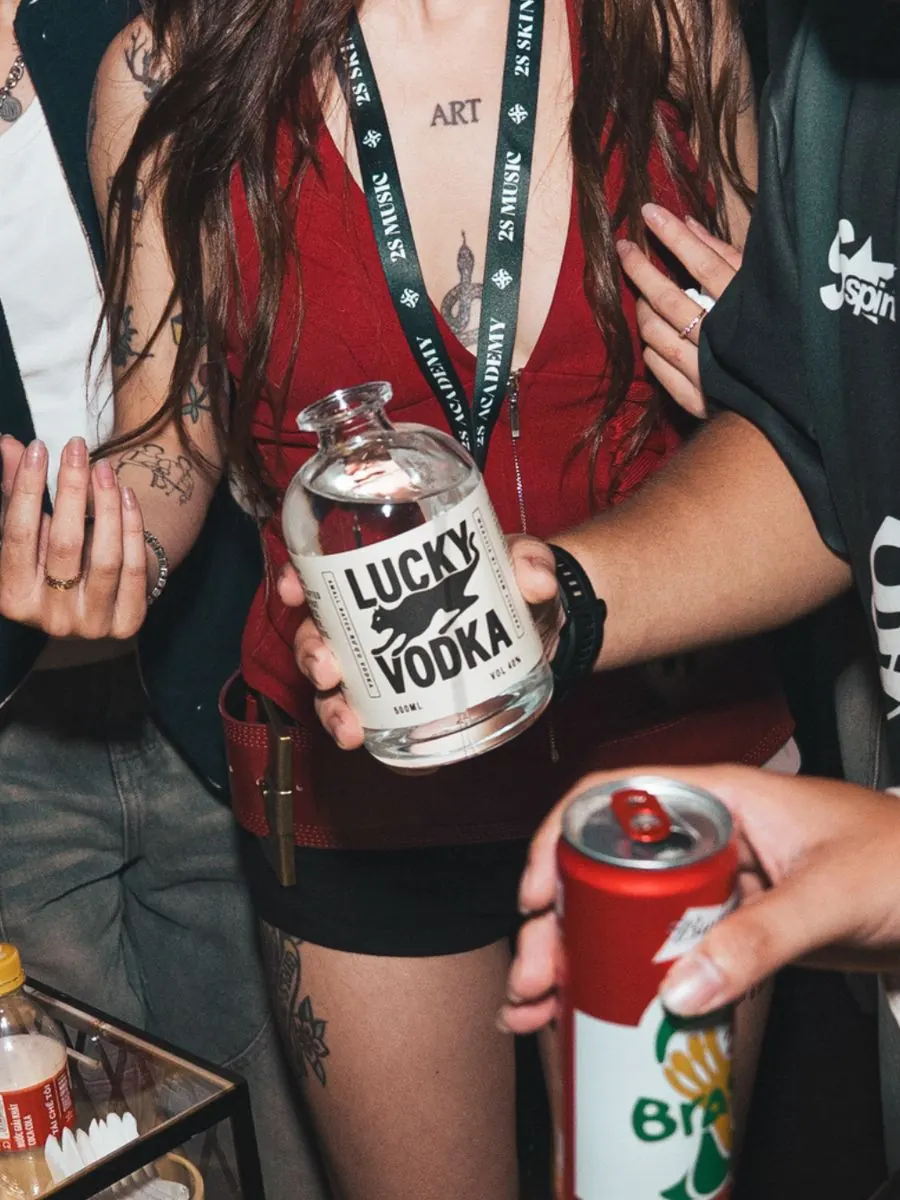 A girl in red holding a bottle of Lucky Vodka