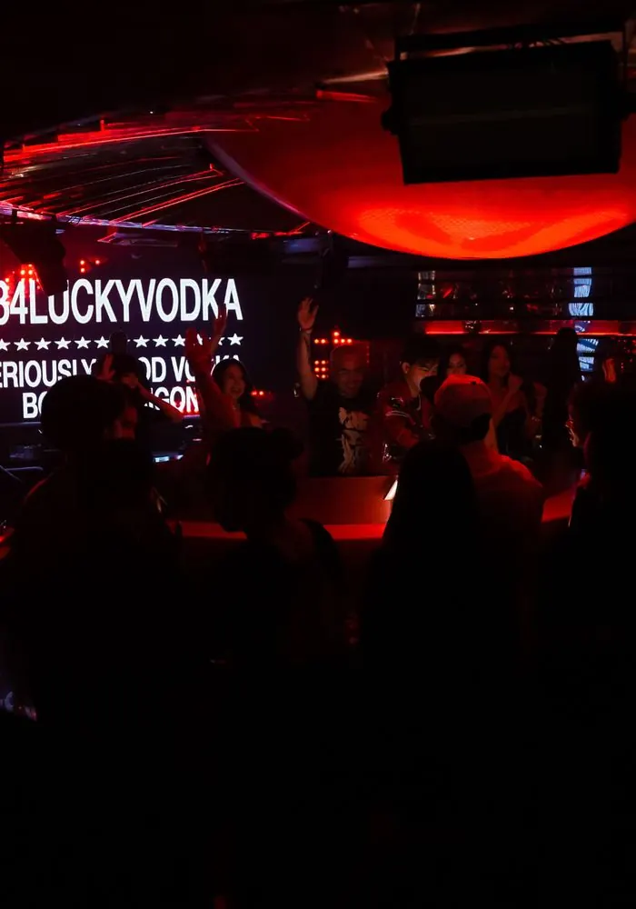 A packed club with the +84 Lucky Vodka screen glowing red