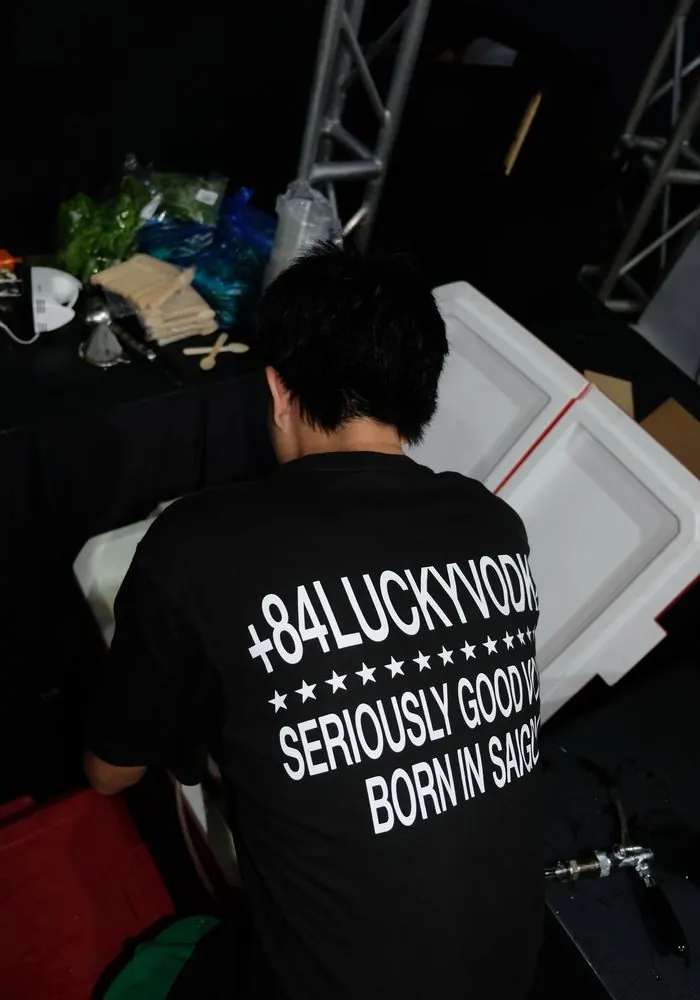 The back of a +84 Lucky Vodka staff tee at an event